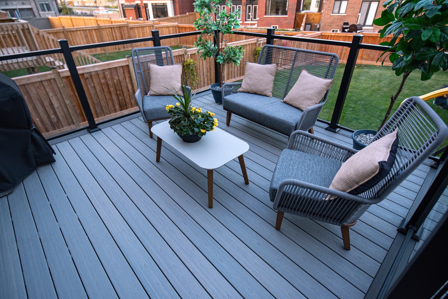 Terrasse composite grise avec rampe en verre et mobilier lounge extérieur