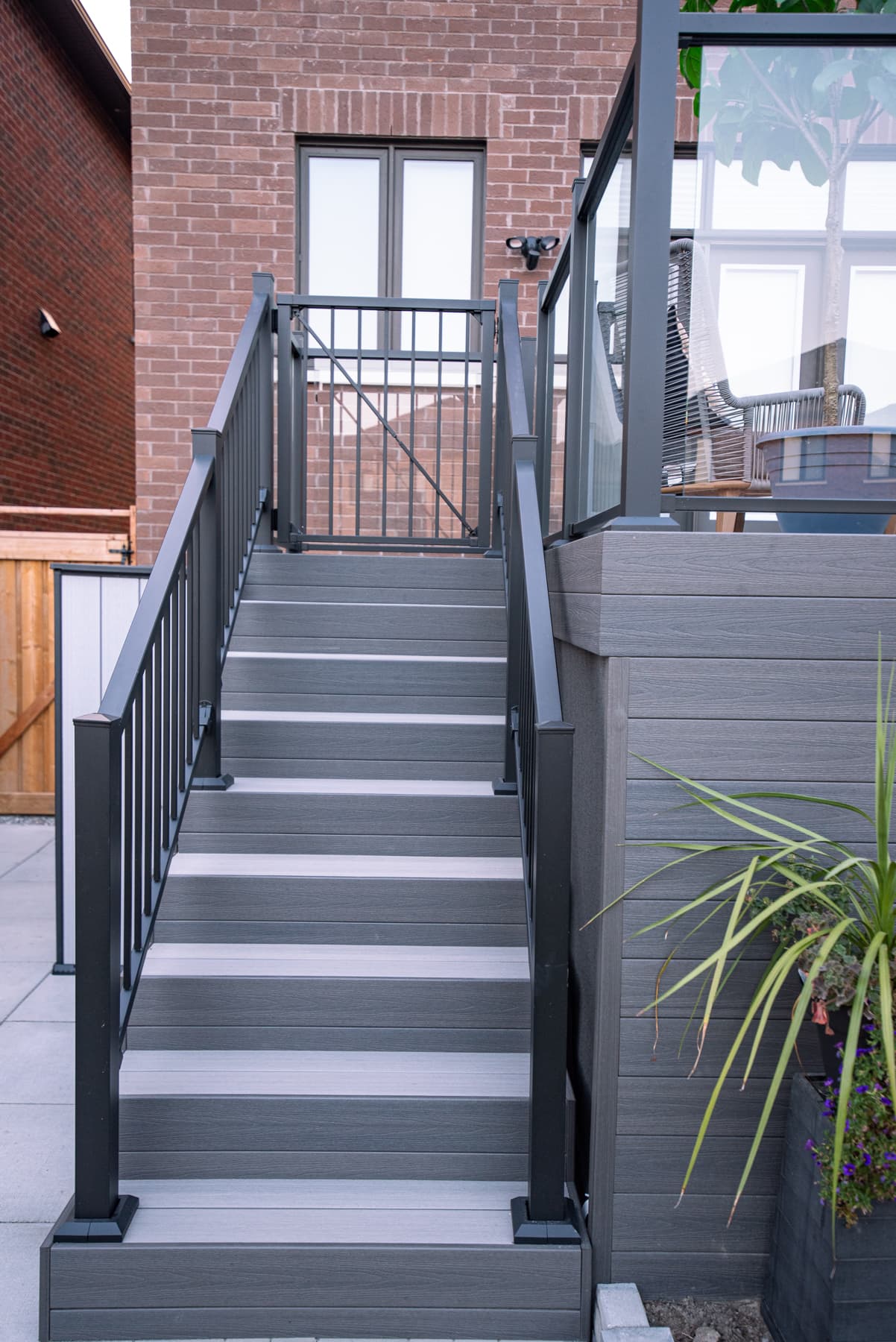 Escalier en composite gris avec rampe en aluminium noir et garde-corps en verre