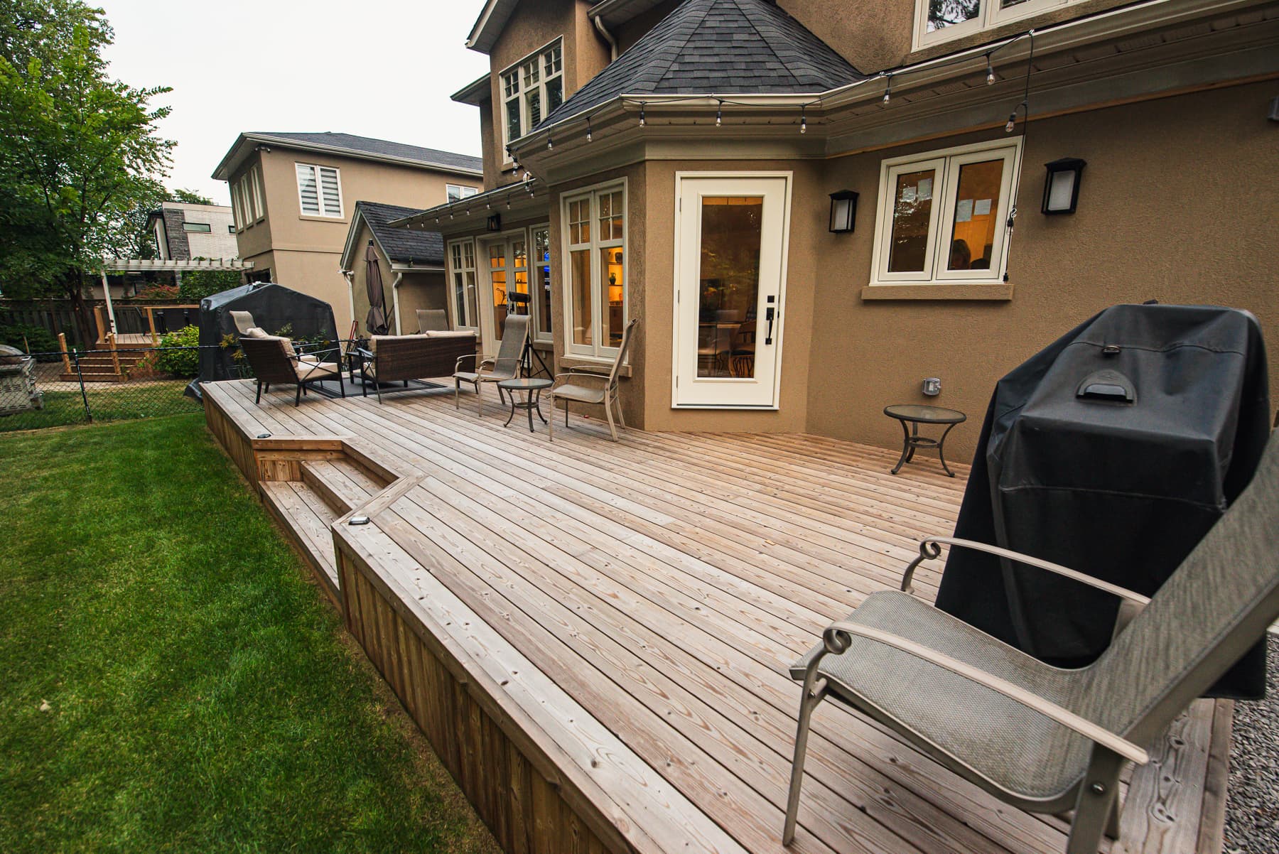 Terrasse de cour arrière en bois traité avec mobilier extérieur près de la maison