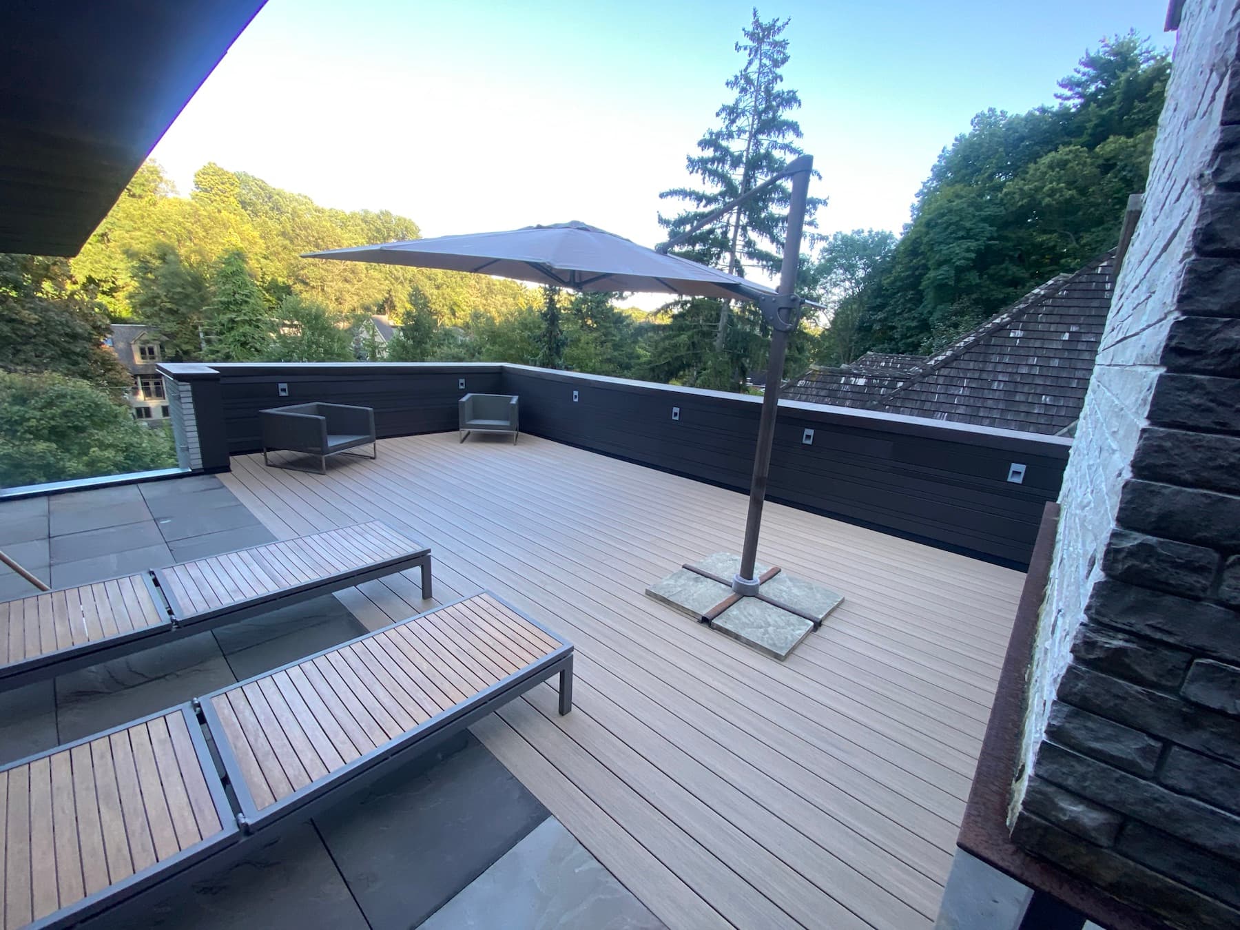 Toit-terrasse composite avec mur d’intimité entouré d’arbres