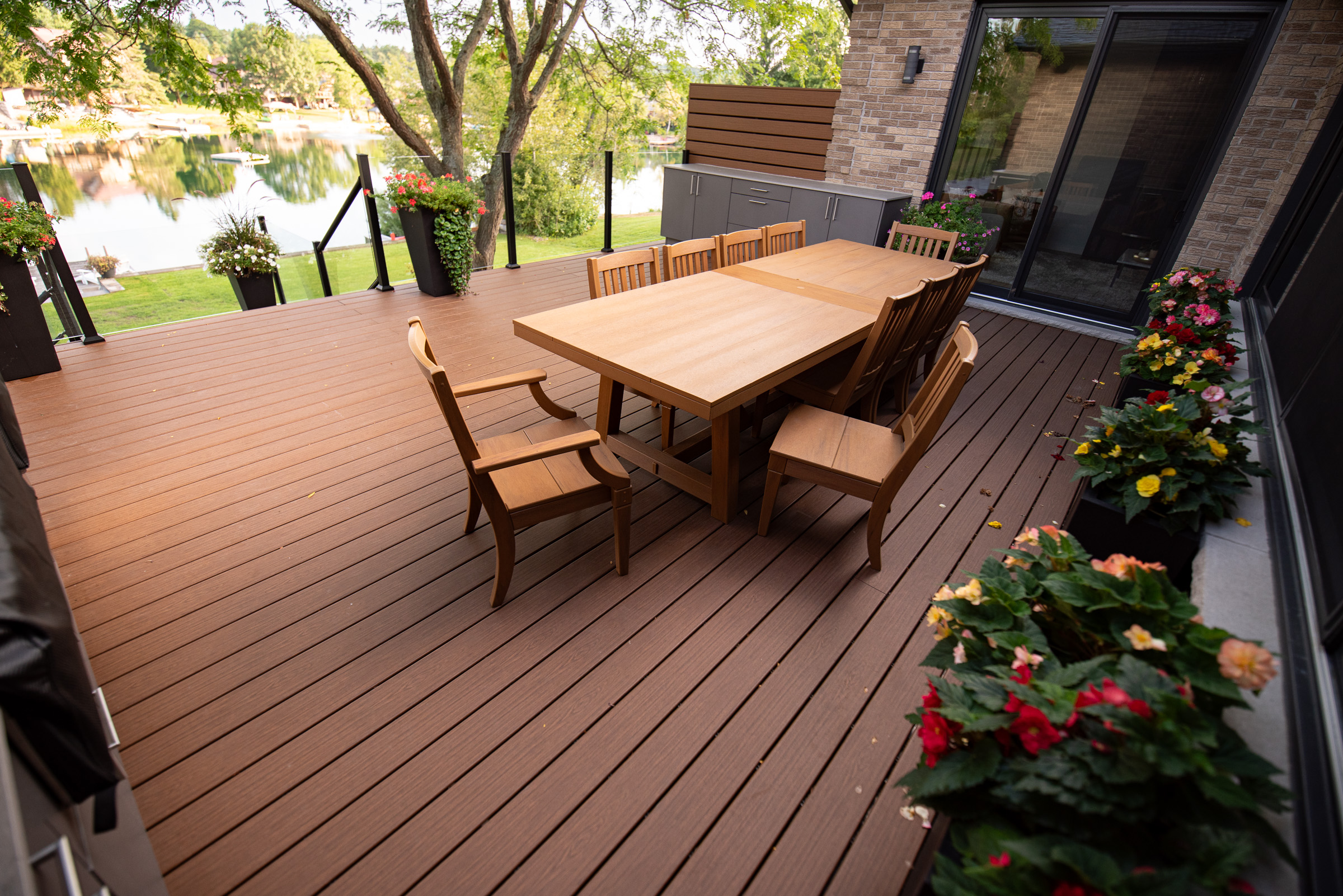 Terrasse composite au bord de l’eau avec coin repas et rampe en verre